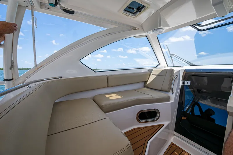 Slide: The Image of 2017 Pursuit 325 OS boat interior with beige seating and ocean view. - 25