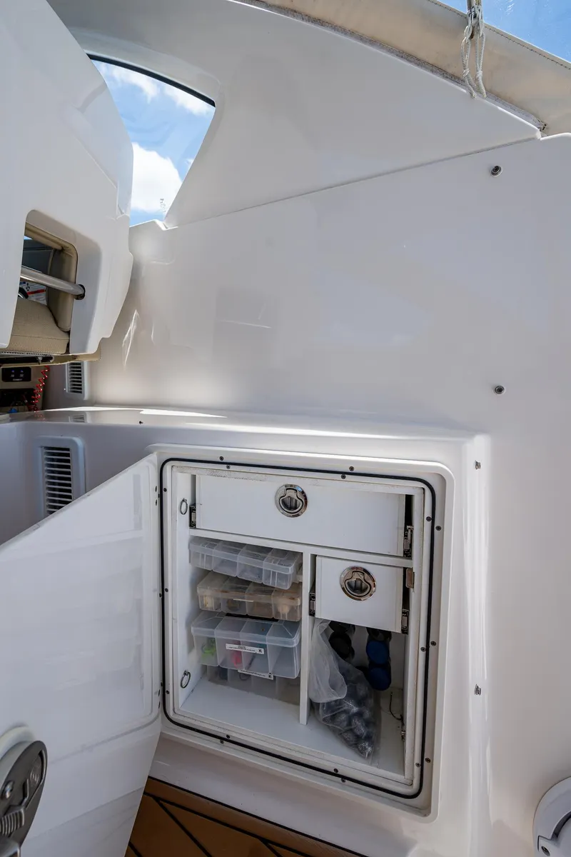 Slide: The Image of 2017 Pursuit 325 OS boat storage compartment with organized shelves and clear sky view. - 27