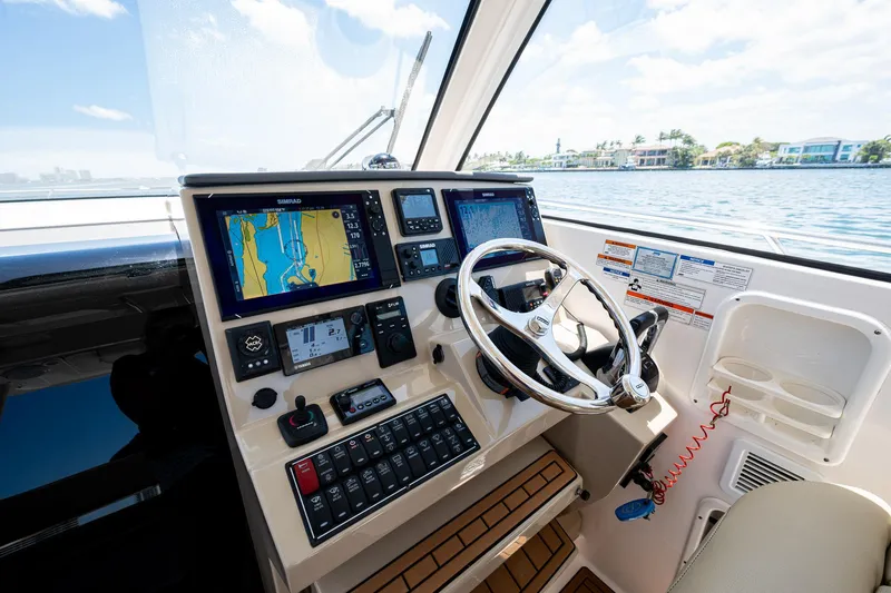 Slide: The Image of 2017 Pursuit 325 OS boat helm with navigation screens and steering wheel. - 29