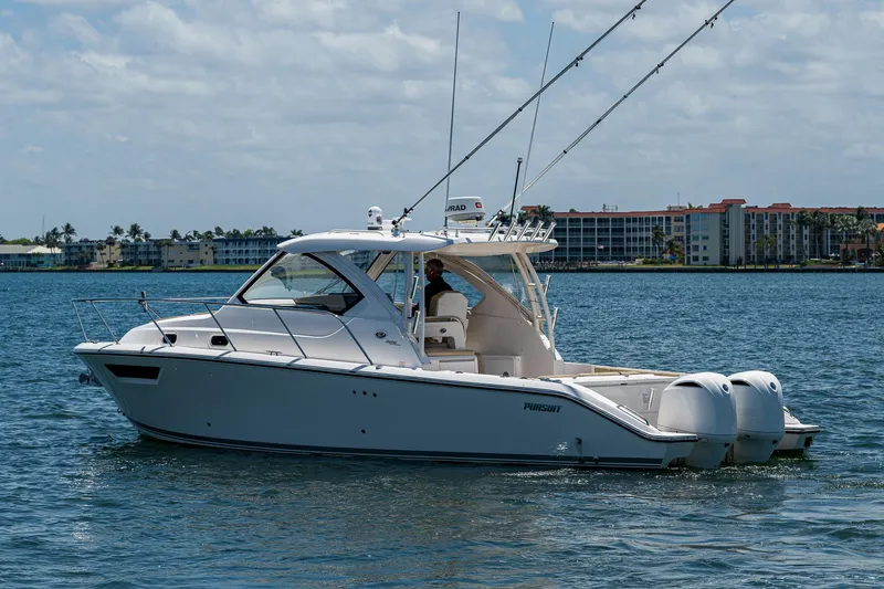 Slide: The Image of 2017 Pursuit 325 OS boat on water with fishing rods, cityscape in background. - 35
