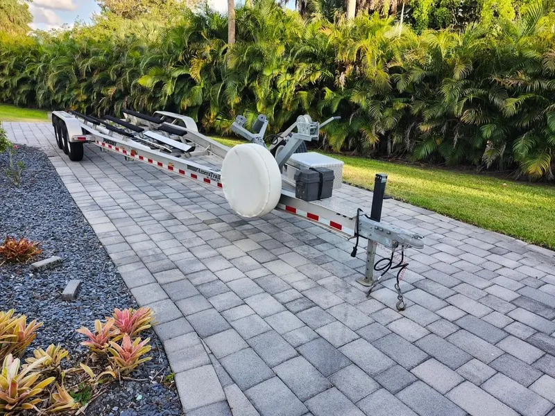Slide: The Image of Trailer for 2017 Pursuit 325 OS boat on paved driveway, surrounded by greenery. - 39