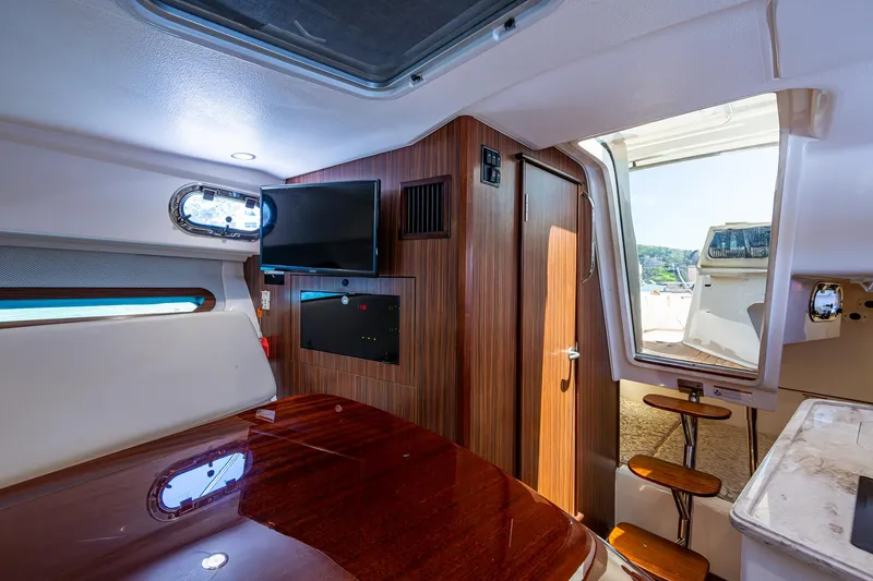 Slide: The Image of Interior of 2017 Pursuit 325 OS boat with wood paneling and TV. - 9