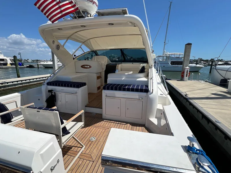 Slide: The Image of 2001 Uniesse 42 Open yacht docked, featuring spacious deck and seating, under clear blue sky. - 10