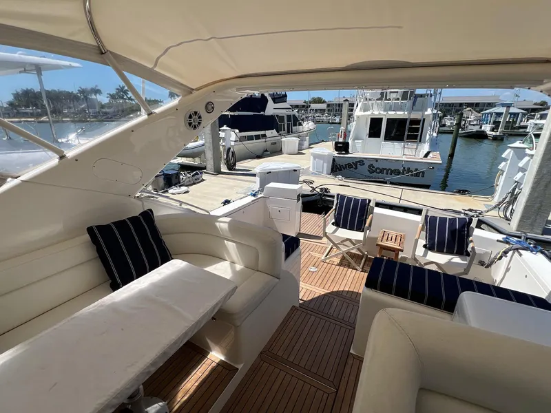 Slide: The Image of 2001 Uniesse 42 Open yacht interior with white seating and striped cushions at a marina. - 18