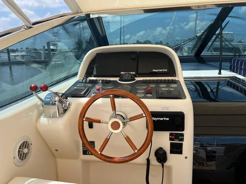 Slide: The Image of 2001 Uniesse 42 Open yacht helm with wooden steering wheel and navigation controls. - 29
