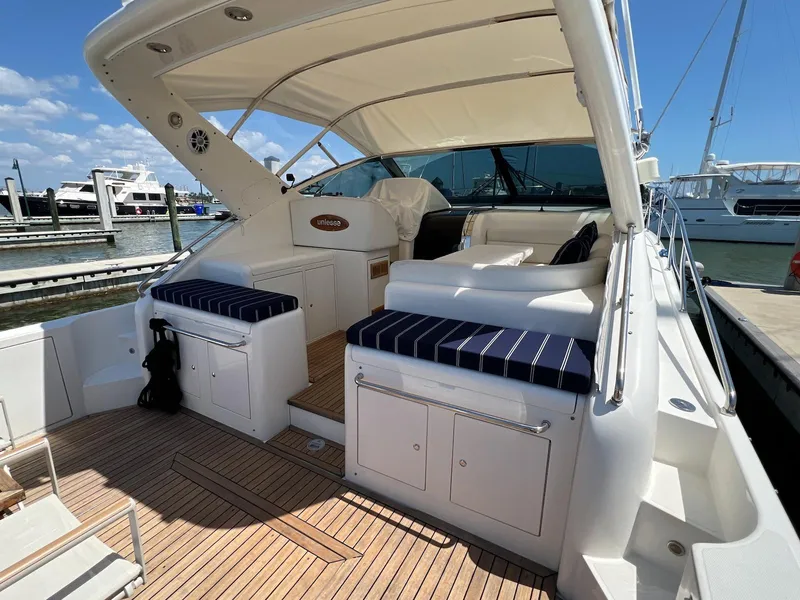 Slide: The Image of 2001 Uniesse 42 Open yacht with spacious deck, striped seating, and elegant design at marina. - 9