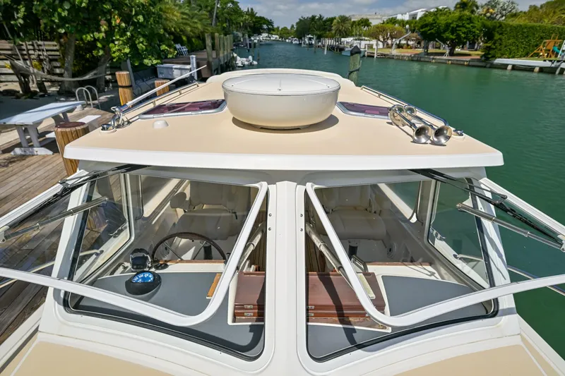 Slide: The Image of 2013 MJM 36z Downeast boat on a serene waterway, showcasing its sleek design and open windows. - 35