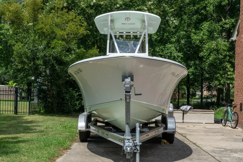 Slide: The Image of 2017 Sea Hunt Ultra 225 boat on trailer, parked in driveway, surrounded by greenery. - 2