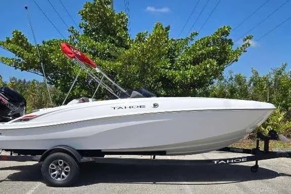 Slide: The Image of 2025 Tahoe T18 boat on trailer, parked outdoors with trees in background. - 1