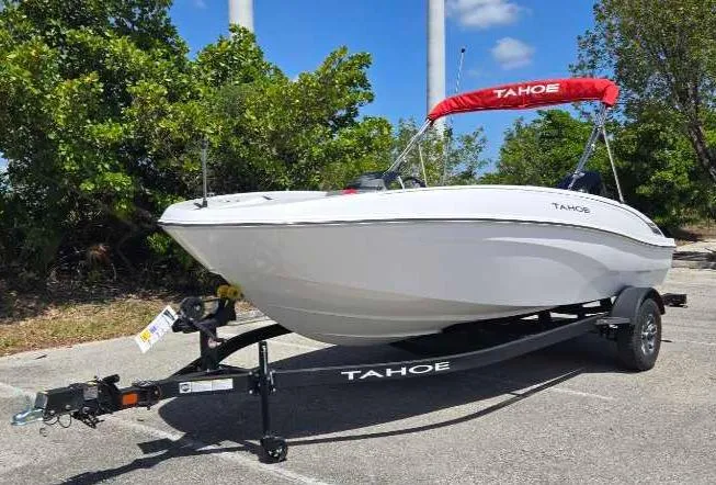 Slide: The Image of 2025 Tahoe T18 boat on trailer, white hull, red canopy, parked outdoors. - 2