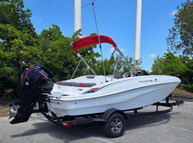 Slide: The Image of 2025 Tahoe T18 boat with red canopy on trailer, parked outdoors. - 3