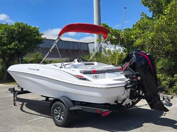 Slide: The Image of 2025 Tahoe T18 boat with red canopy on trailer, parked outdoors. - 6