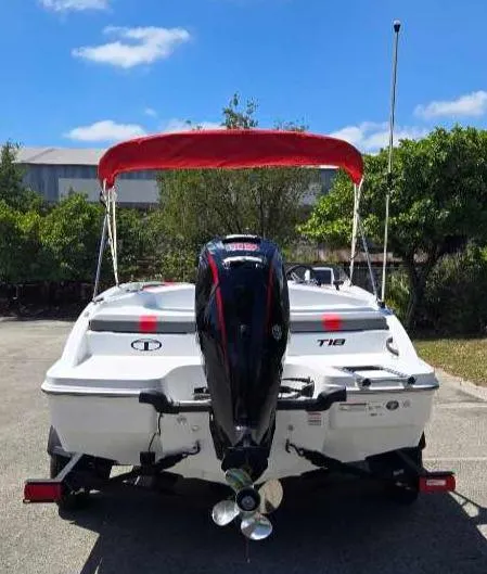 Slide: The Image of 2025 Tahoe T18 boat with red canopy and outboard motor, parked outdoors. - 7
