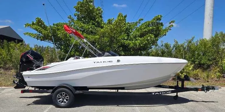 Slide: The Image of 2025 Tahoe T18 boat on trailer, parked outdoors with greenery in the background. - 70