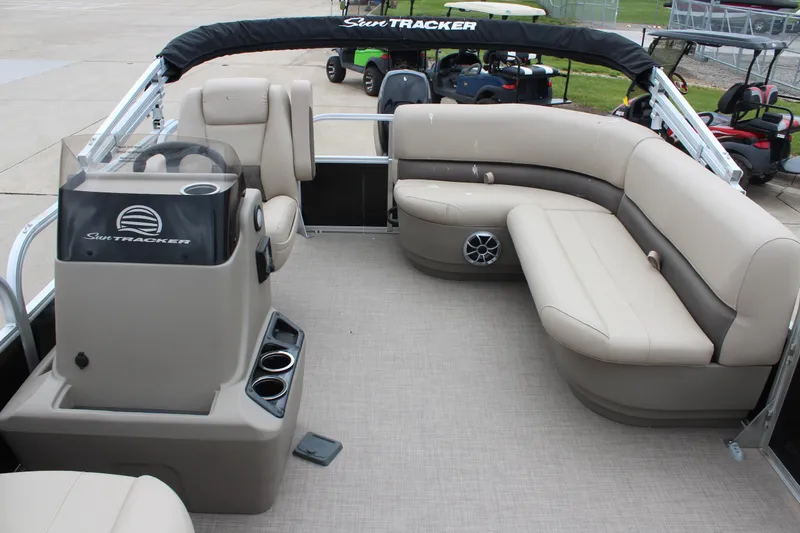 Slide: The Image of 2025 Sun Tracker Party Barge 16 DLX interior with beige seating and steering console. - 10
