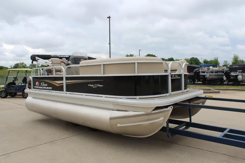 Slide: The Image of 2025 Sun Tracker Party Barge 16 DLX pontoon boat on trailer, parked outdoors. - 5