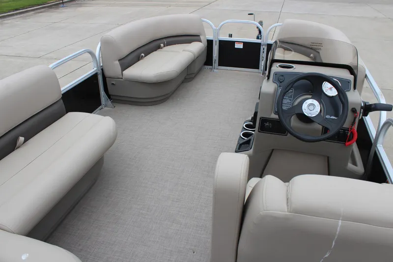 Slide: The Image of 2025 Sun Tracker Party Barge 16 DLX interior with beige seating and steering console. - 8