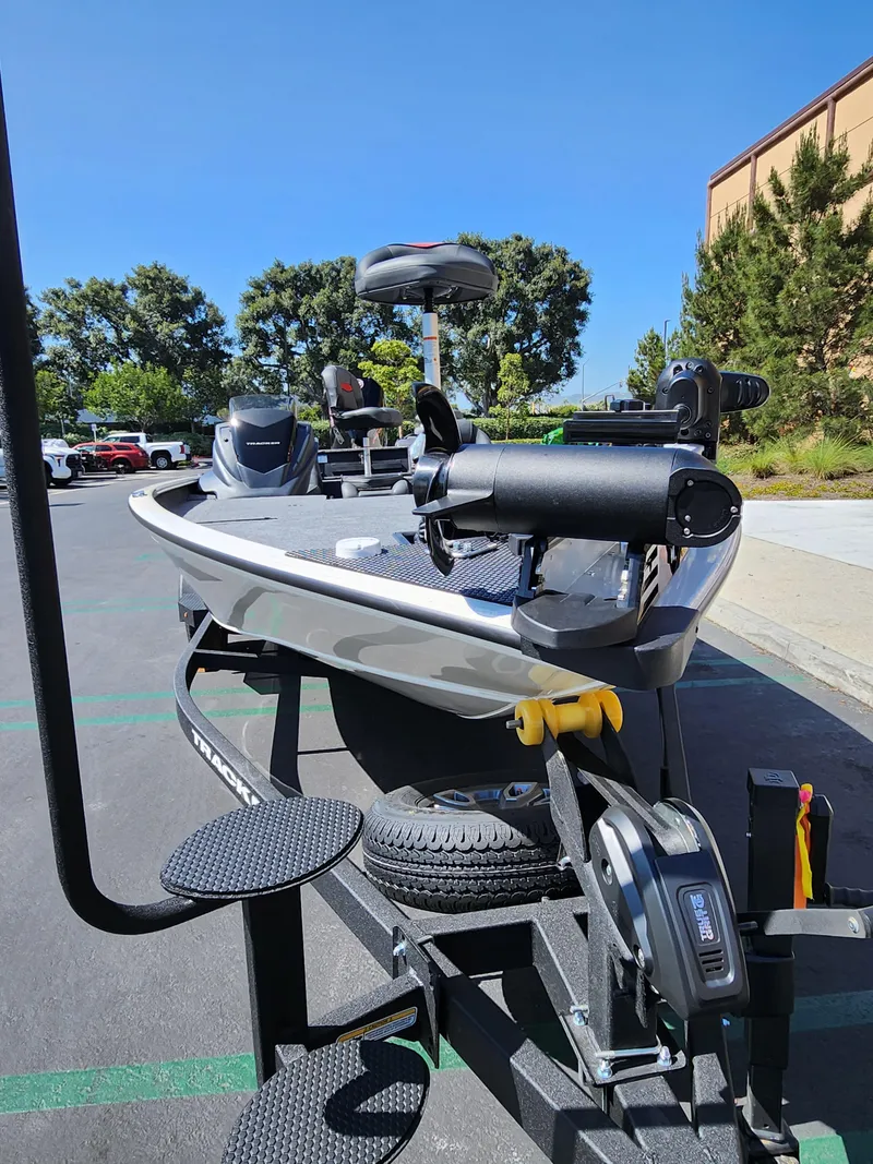 Slide: The Image of 2025 Tracker Savage 215 boat on trailer in parking lot, sunny day. - 2