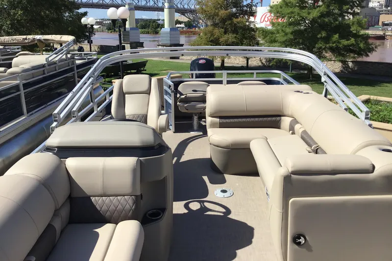 Slide: The Image of 2025 Sun Tracker Fishin' Barge 22 DLX pontoon boat with spacious seating and scenic river backdrop. - 2