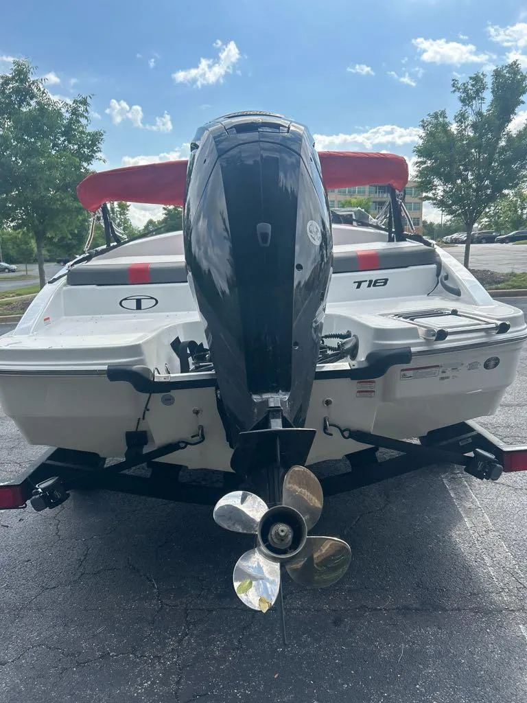 Slide: The Image of 2025 Tahoe T18 boat with outboard motor and red canopy, parked on pavement. - 3