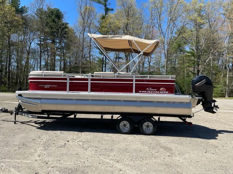 The Image of 2025 Sun Tracker Party Barge 22 RF DLX pontoon boat on trailer, parked outdoors. - 0