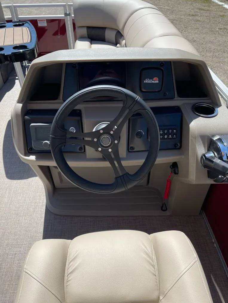 Slide: The Image of 2025 Sun Tracker Party Barge 22 RF DLX steering console with beige seating and controls. - 9