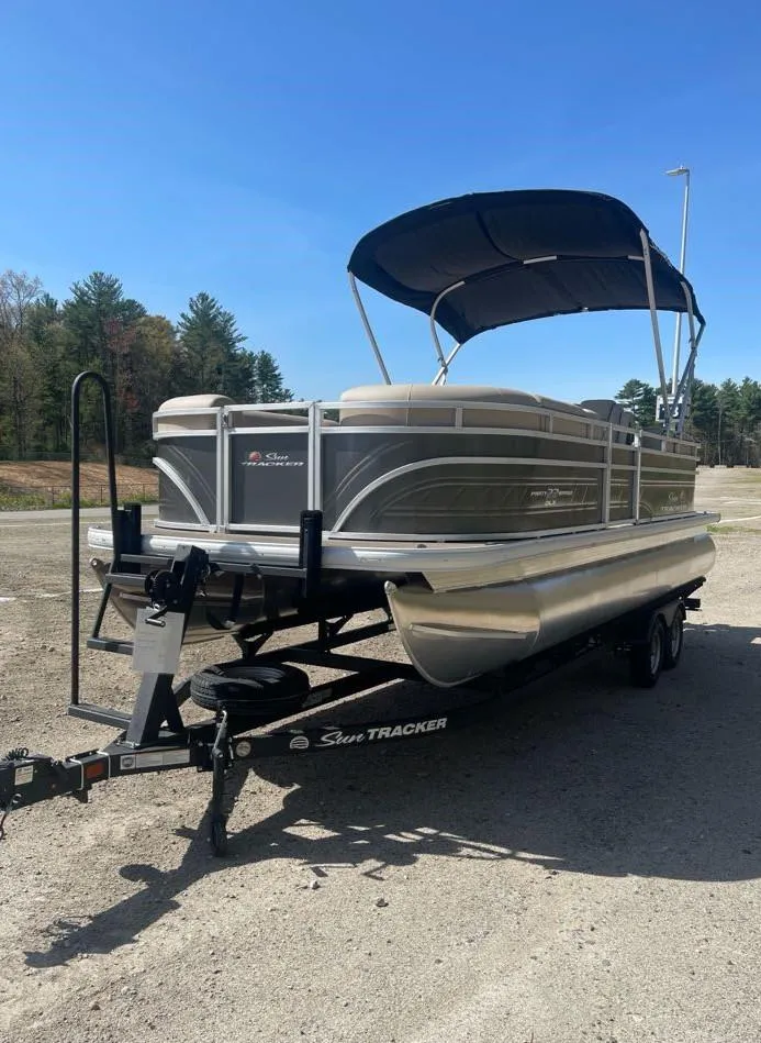 Slide: The Image of 2025 Sun Tracker Party Barge 22 DLX pontoon boat on trailer, parked outdoors. - 3