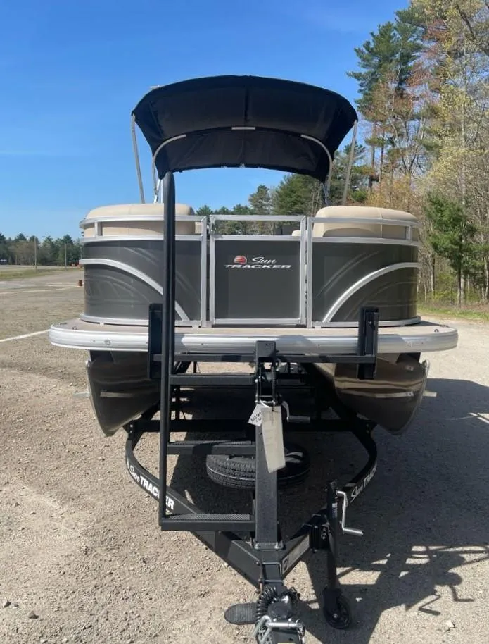 Slide: The Image of 2025 Sun Tracker Party Barge 22 DLX pontoon boat on trailer, parked outdoors. - 4