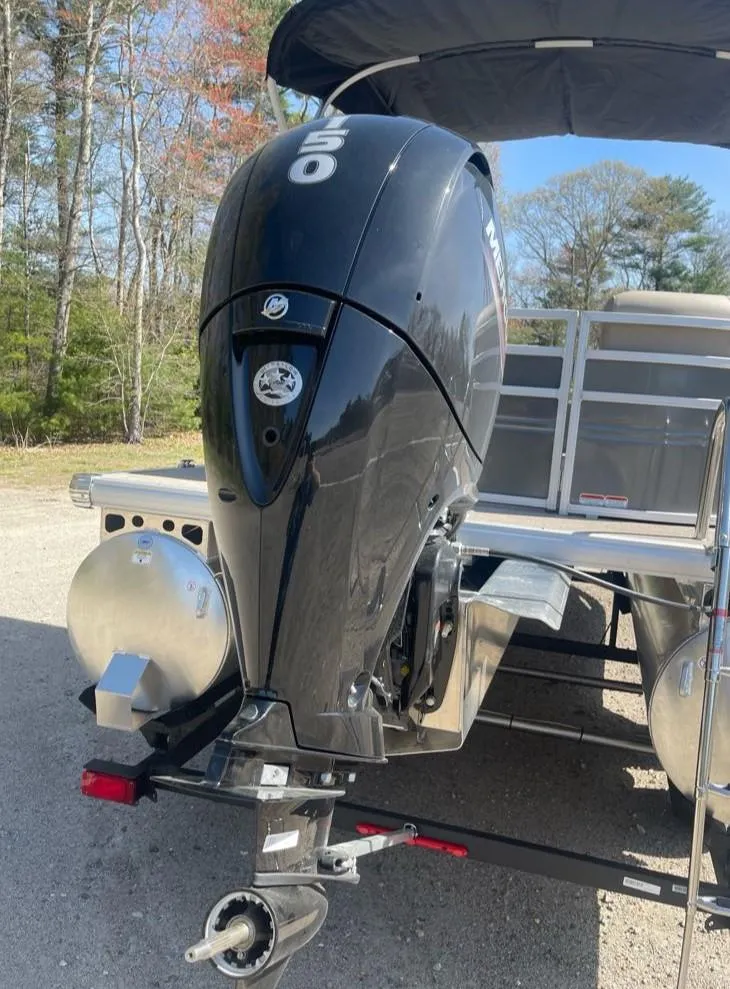 Slide: The Image of 2025 Sun Tracker Party Barge 22 DLX with powerful outboard motor, parked outdoors. - 9