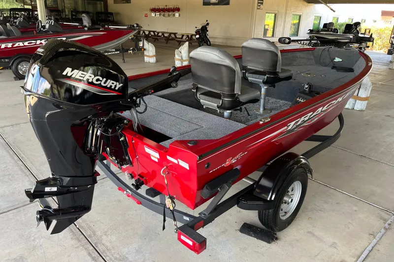 Slide: The Image of 2025 Tracker Super Guide V-16 T boat with Mercury engine, red exterior, parked indoors. - 2