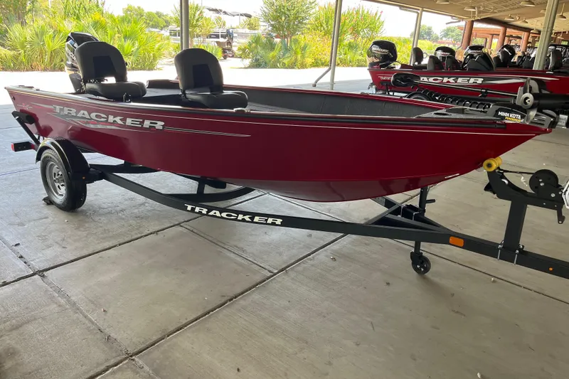 Slide: The Image of 2025 Tracker Super Guide V-16 T boat on trailer, red exterior, parked under shelter. - 3