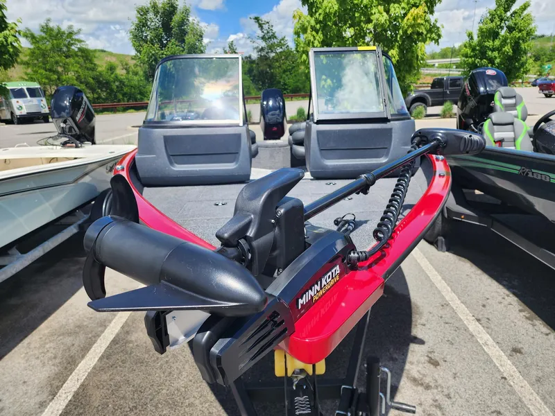 Slide: The Image of 2025 Tracker Pro Guide V-16 WT boat with Minn Kota motor in a parking lot. - 2