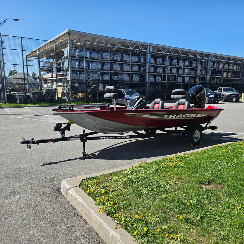 Slide: The Image of 2025 Tracker Pro Team 175 boat on trailer in parking lot, sunny day. - 2