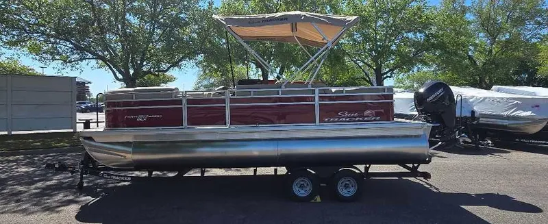 The Image of 2025 Sun Tracker Party Barge 22 RF DLX pontoon boat with canopy, parked on trailer. - 0