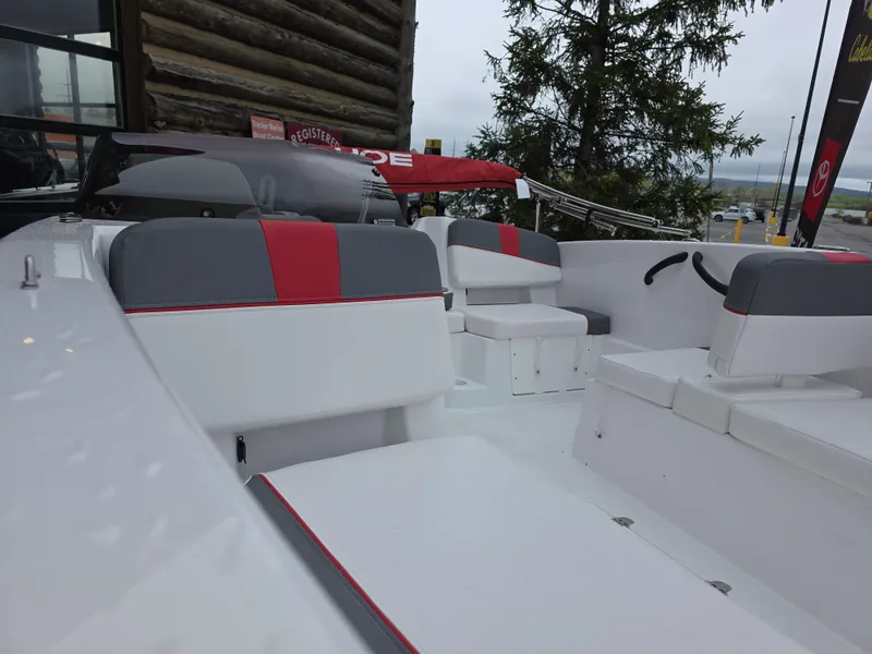 Slide: The Image of 2025 Tahoe T18 boat interior with gray and red seating, docked near a wooden building. - 3