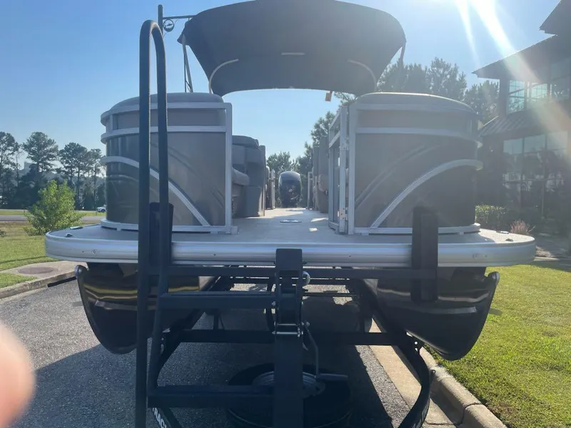Slide: The Image of 2025 Sun Tracker Party Barge 22 DLX pontoon boat on trailer, parked outdoors. - 4