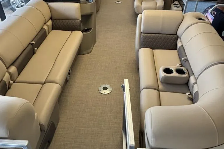 Slide: The Image of 2025 Sun Tracker Party Barge 22 DLX interior with beige seating and cup holders. - 2