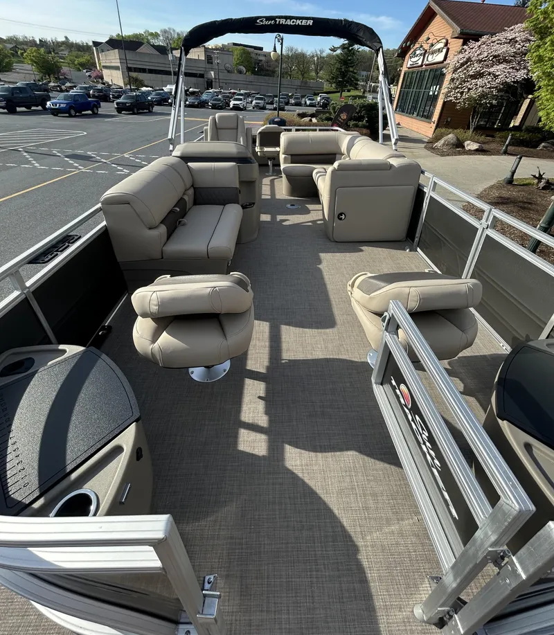 Slide: The Image of 2025 Sun Tracker Fishin' Barge 22 DLX pontoon boat with spacious seating in a parking lot. - 2