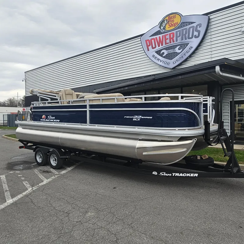 The Image of 2025 Sun Tracker Fishin' Barge 22 DLX pontoon boat on trailer at service center. - 0