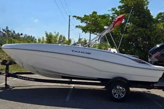The Image of 2025 Tahoe T18 boat on trailer, parked outdoors with trees in background. - 0