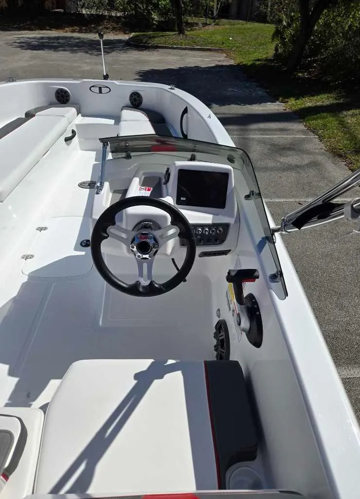 Slide: The Image of 2025 Tahoe T18 boat interior with steering wheel and control panel, parked outdoors. - 4