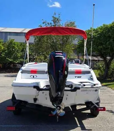 Slide: The Image of 2025 Tahoe T18 boat with red canopy and outboard motor in a sunny parking lot. - 5