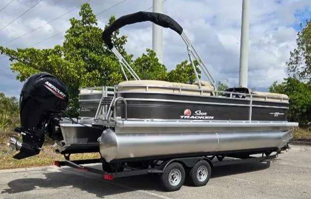 Slide: The Image of 2025 Sun Tracker Party Barge 22 RF DLX pontoon boat on trailer, parked outdoors. - 2