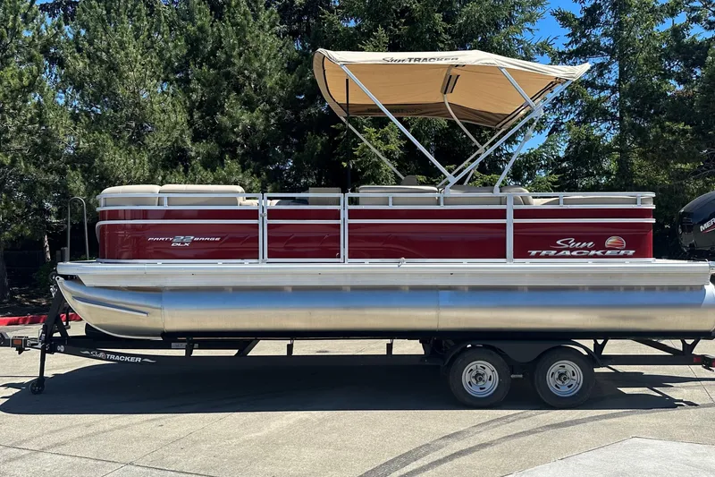 The Image of 2025 Sun Tracker Party Barge 22 DLX pontoon boat on trailer, parked outdoors. - 0