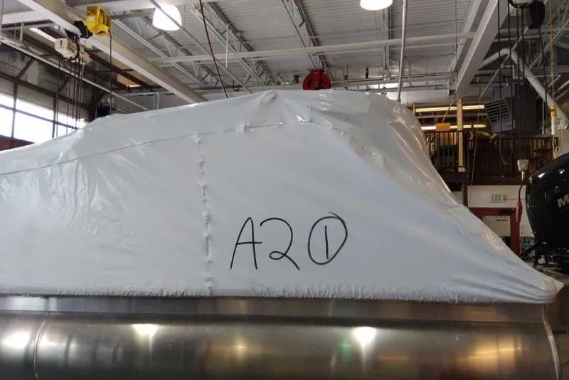 Slide: The Image of 2025 Sun Tracker Party Barge 22 DLX covered in protective wrap inside a warehouse. - 73