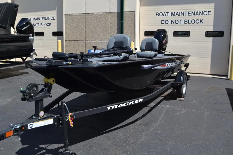 Slide: The Image of 2025 Tracker Panfish 17 boat on trailer, parked near maintenance area. - 2