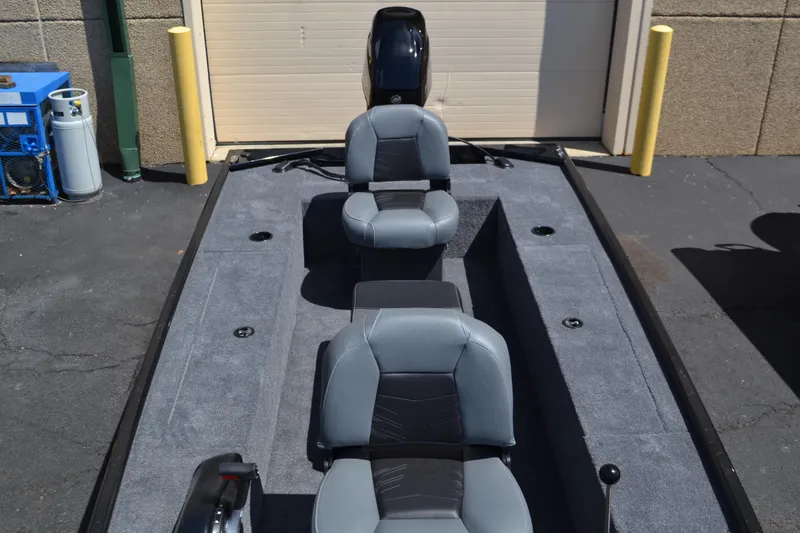 Slide: The Image of 2025 Tracker Panfish 17 boat interior with three gray seats, parked outdoors. - 5