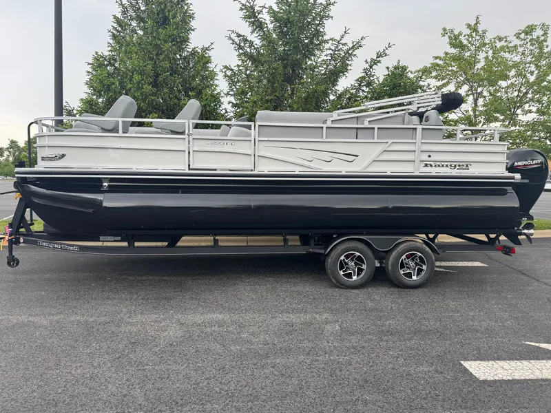 Slide: The Image of 2025 Ranger Reata 223FC pontoon boat on trailer, parked outdoors. - 1