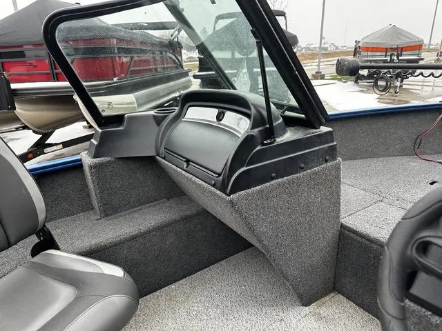 Slide: The Image of 2022 Lund 1650 Rebel XL Sport interior with seating and dashboard, parked outdoors. - 8