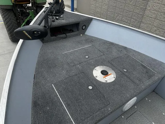 Slide: The Image of 2005 Lund 16 REBEL boat interior with carpeted deck and mounted trolling motor. - 12